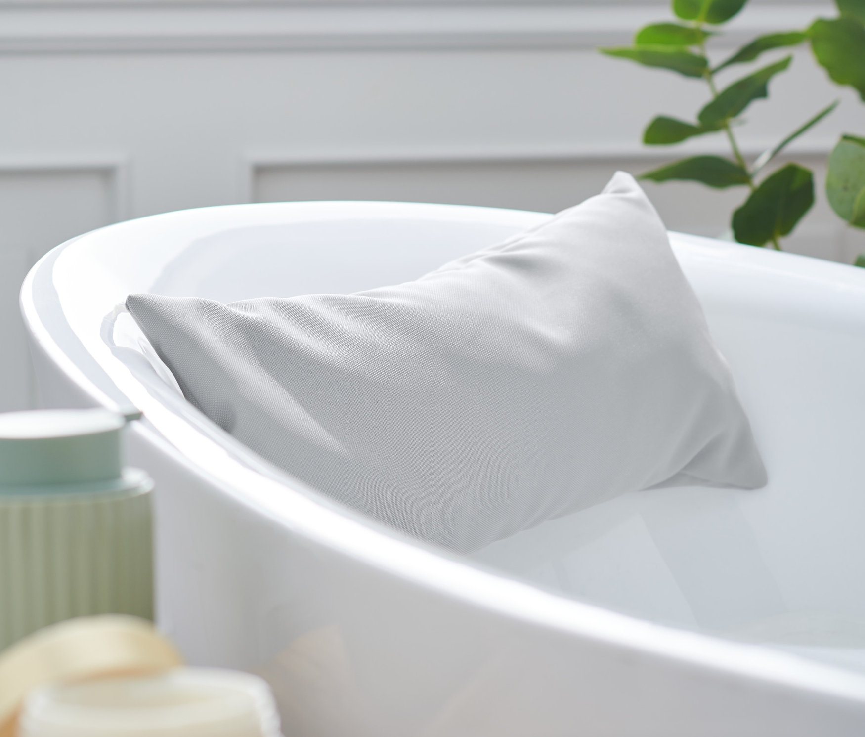 Sivý vankúšik do vane je opretý o okraj bielej vane.