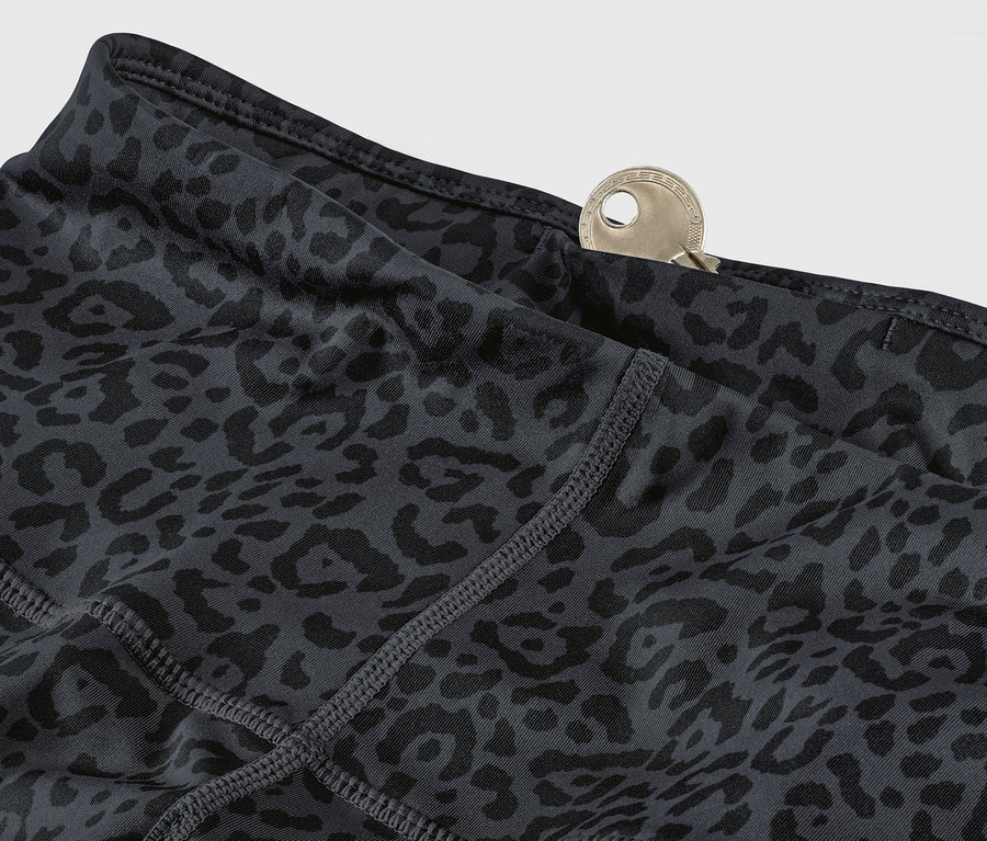 Detail sivých a čiernych športových legín s leopardím vzorom a kľúčom vo vrecku.