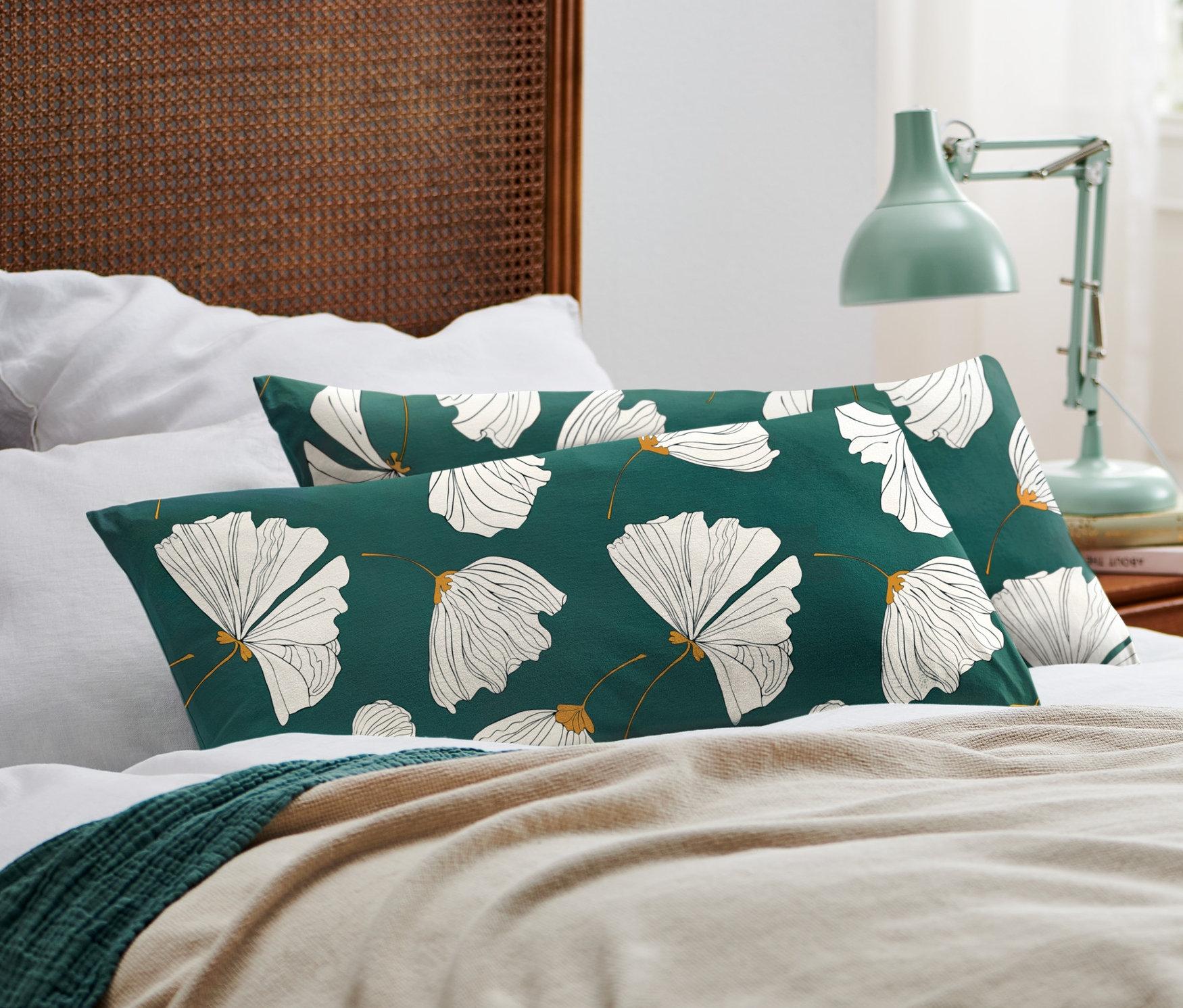 Dve džersejové obliečky na vankúše s kvetinovým vzorom ležia na posteli.