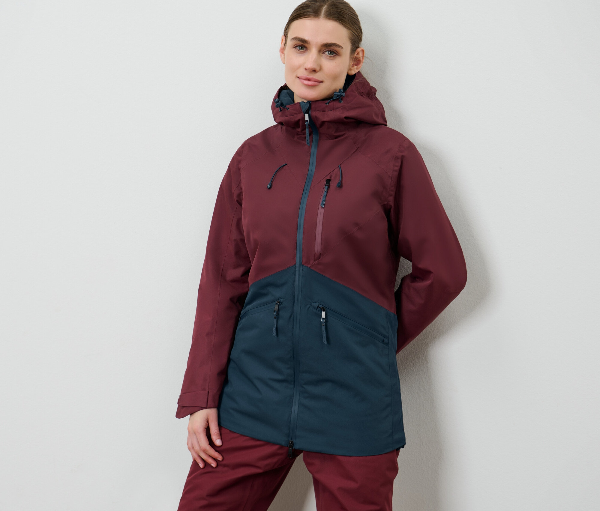 Žena pózuje v lyžiarskej a snoubordovej bunde.