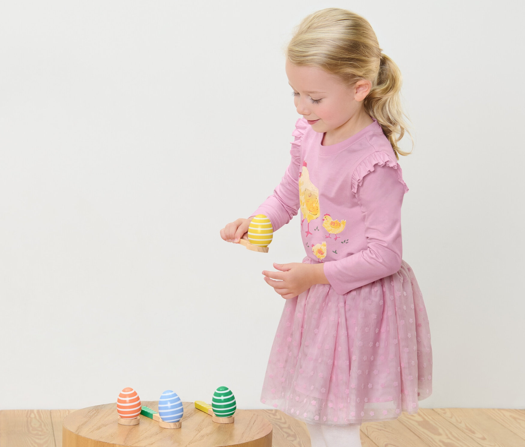 Dievča hrá Hra na beh s vajíčkom. Stojí a sústredí sa na vyvažovanie vajíčka na lyžici.