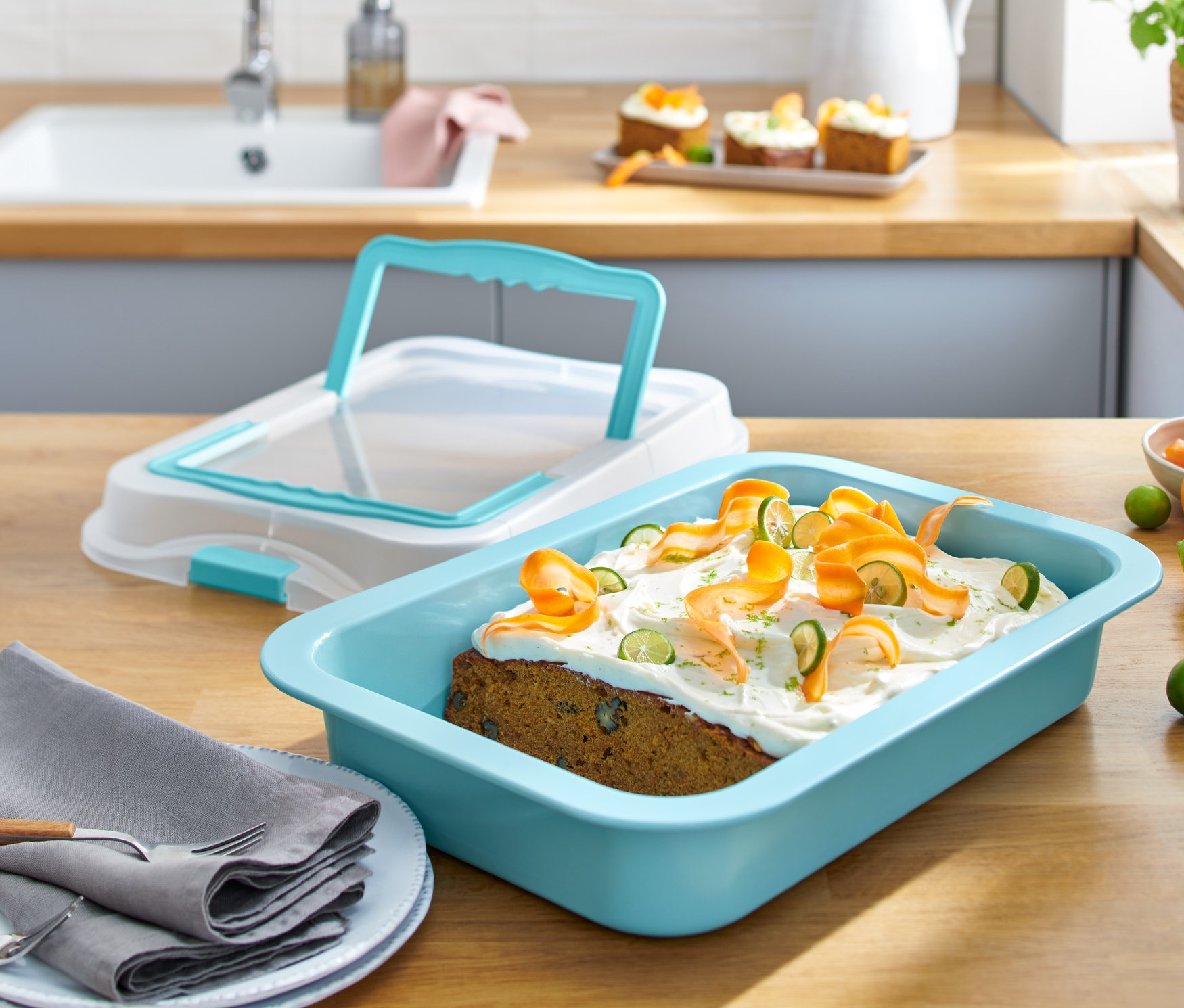 Plech na pečenie s vekom a upečený koláč s polevou a ozdobami z mrkvy a limetky na drevenom stole.