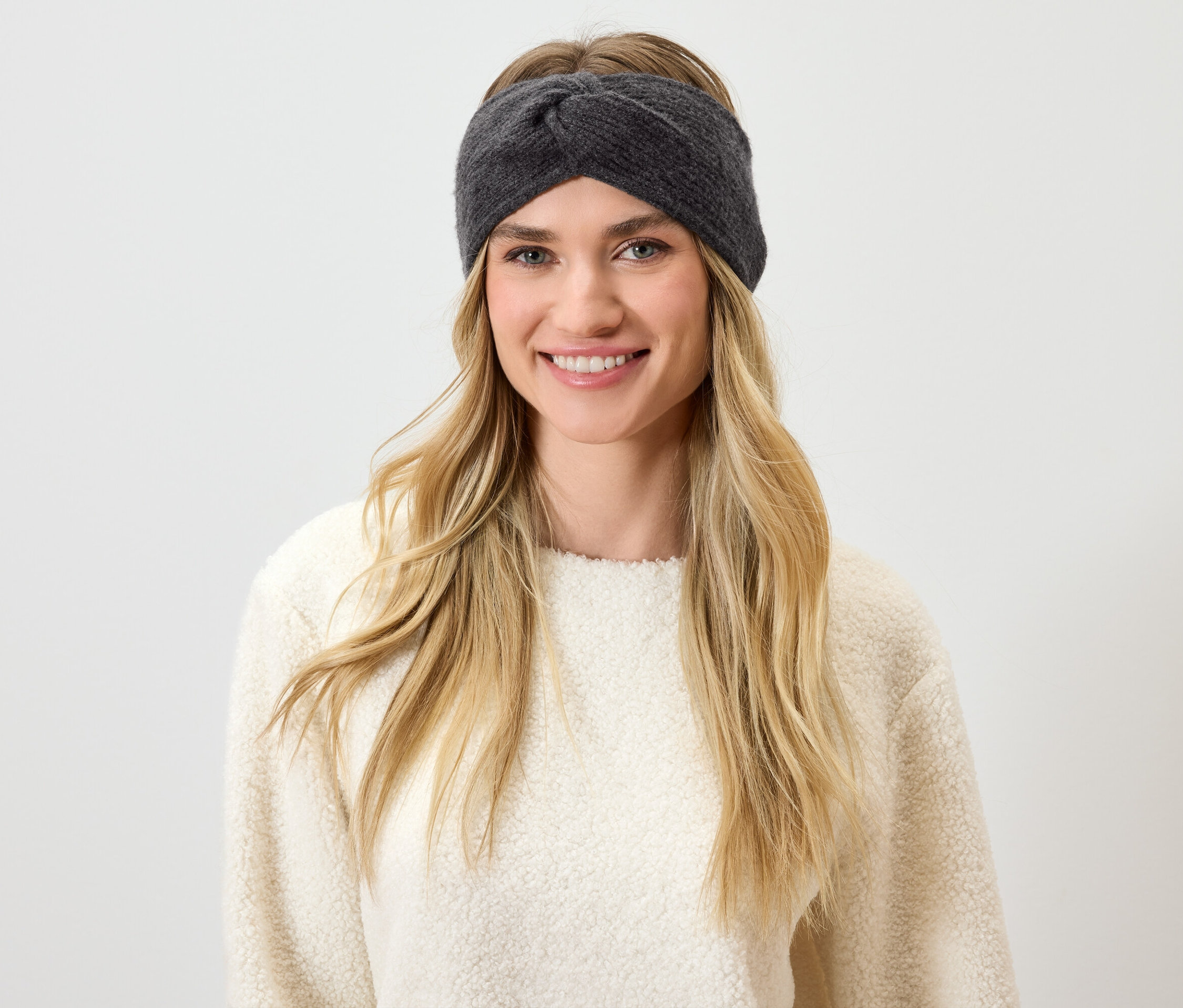 Žena s blond vlasmi a sivou čelenkou sa usmieva.