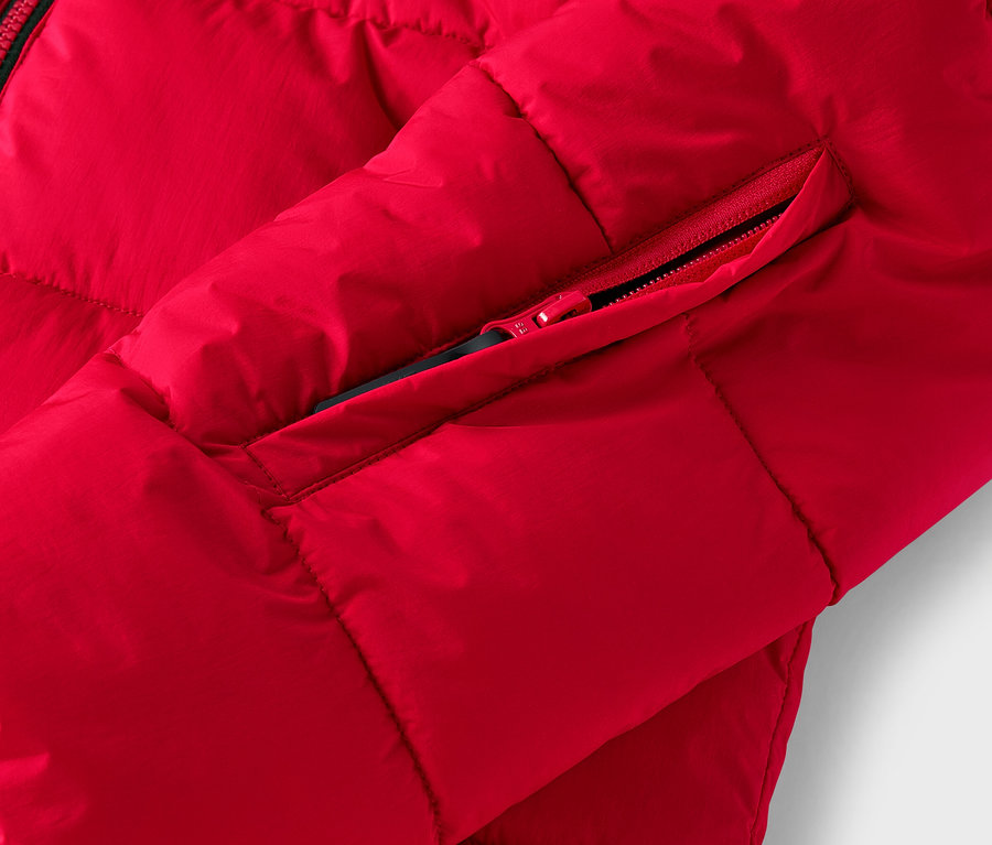 Detail červenej prešívanej bundy s vreckom na zips.