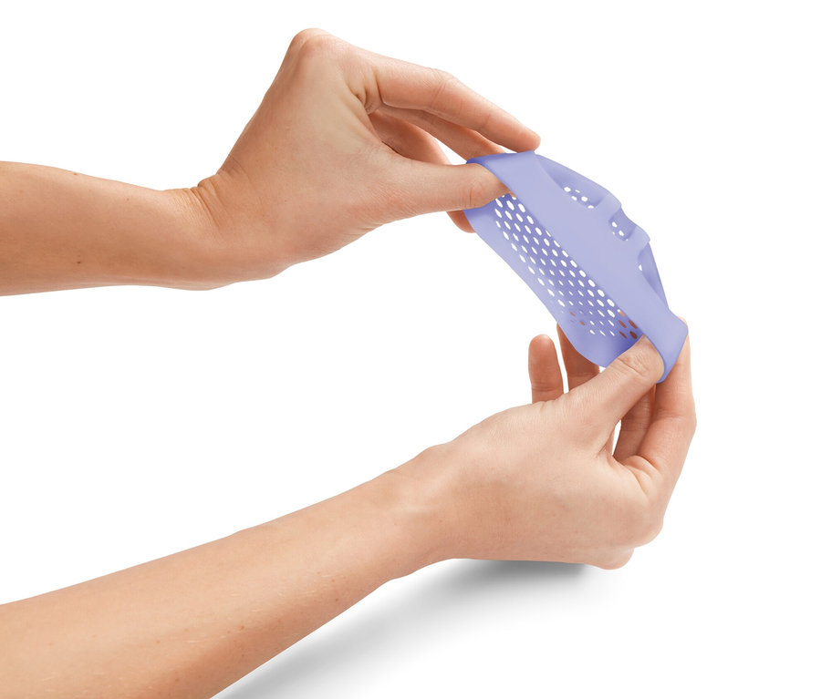 Ruky naťahujú fialovú silikónovú vložku s otvormi.