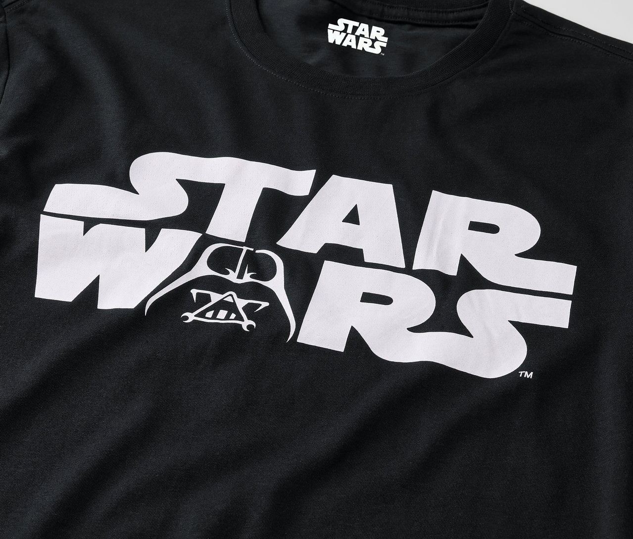 Čierne tričko s bielym logom Star Wars a obrázkom Darth Vadera.