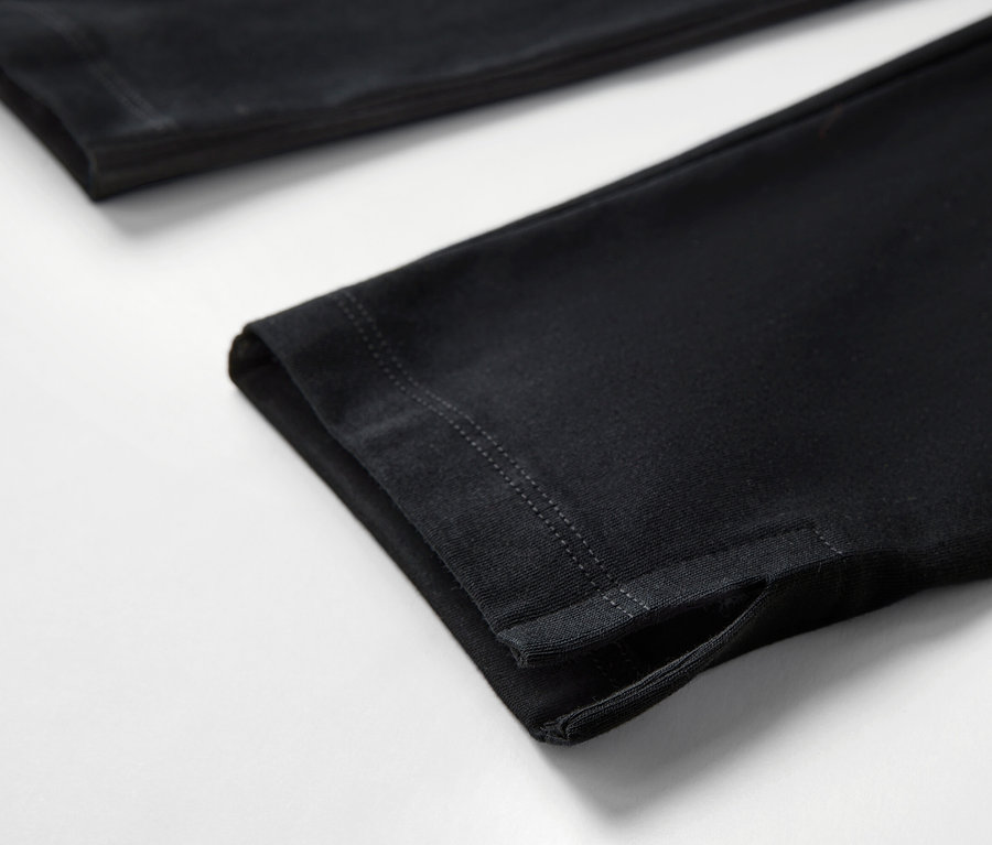 Detail čiernych 3/4 legín s lemom na bielom pozadí.