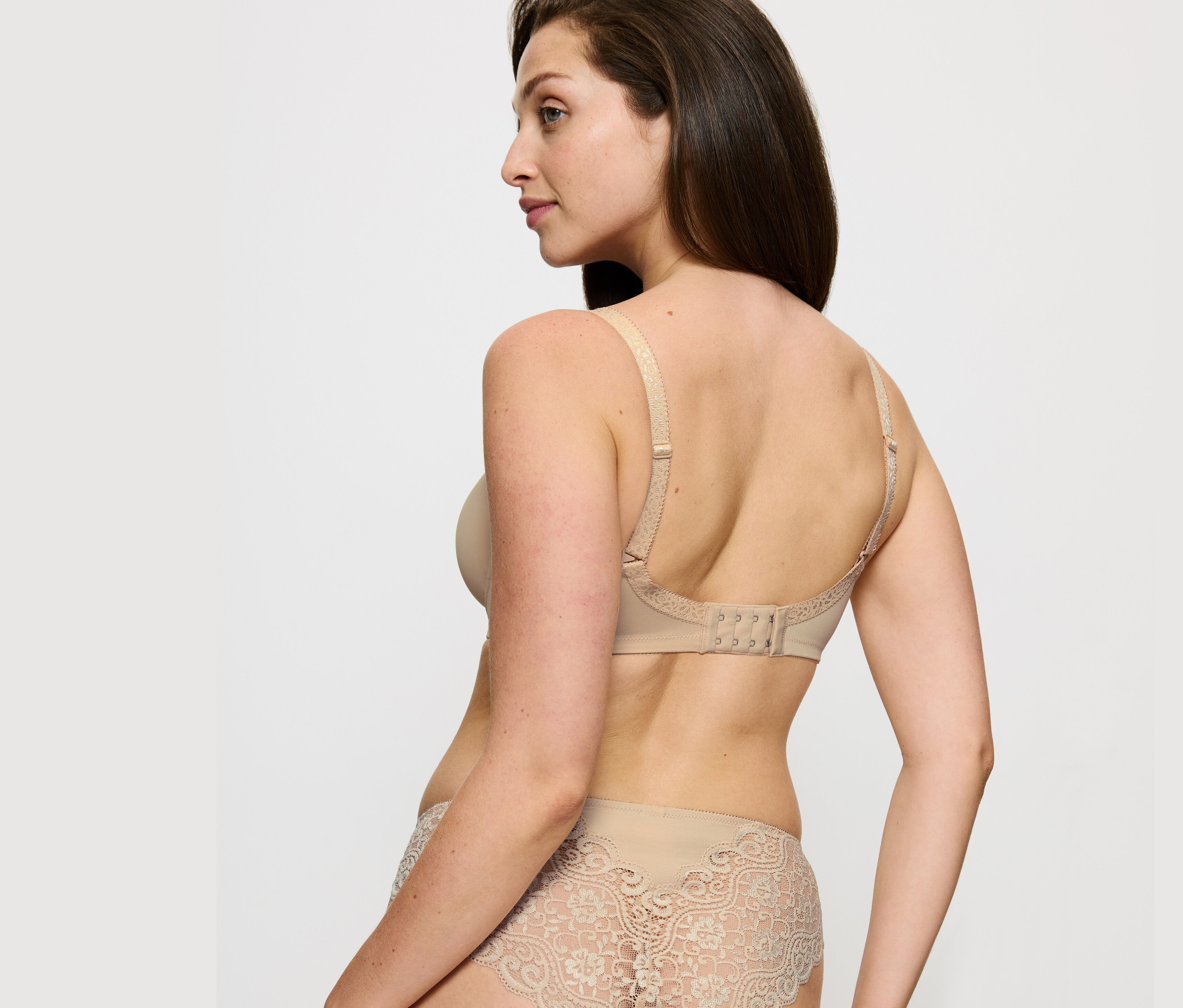 Žena pózuje v podprsenke Triumph Amourette Minimizer, telovej farby a čipkovaných nohavičkách.