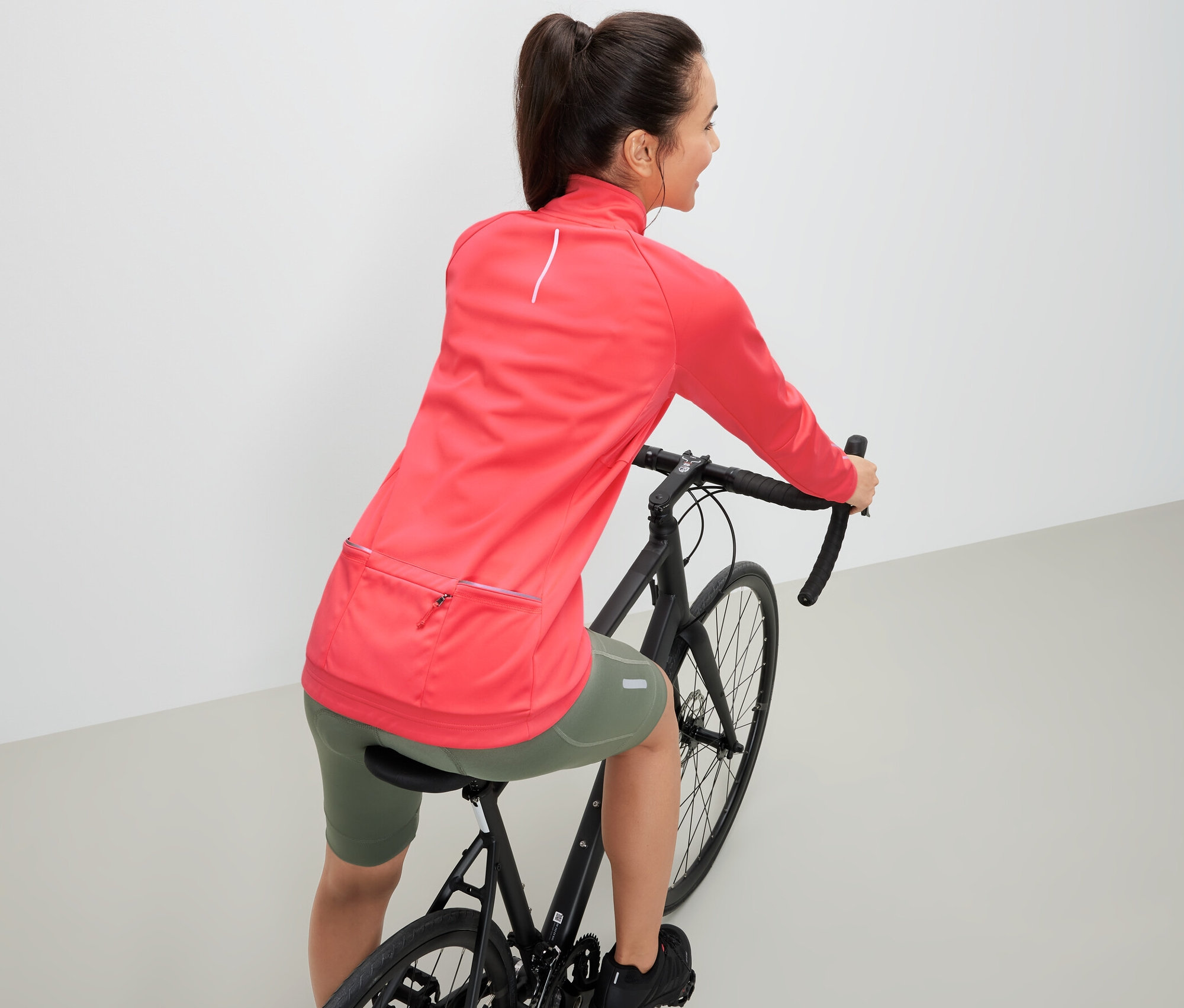 Žena na bicykli má na sebe cyklistickú funkčnú bundu.