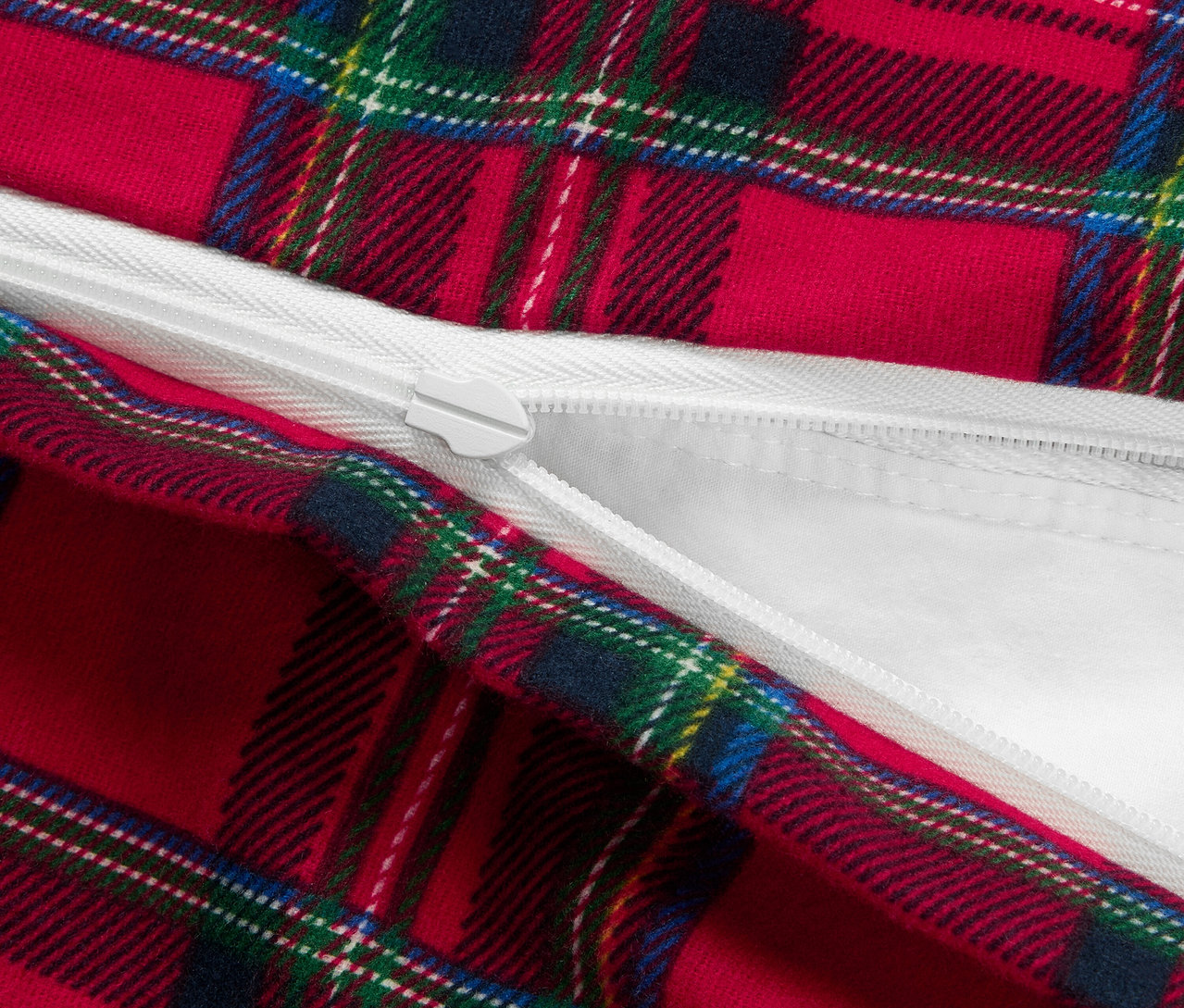 Detail červenej obliečky s károvaným vzorom a zipsom.