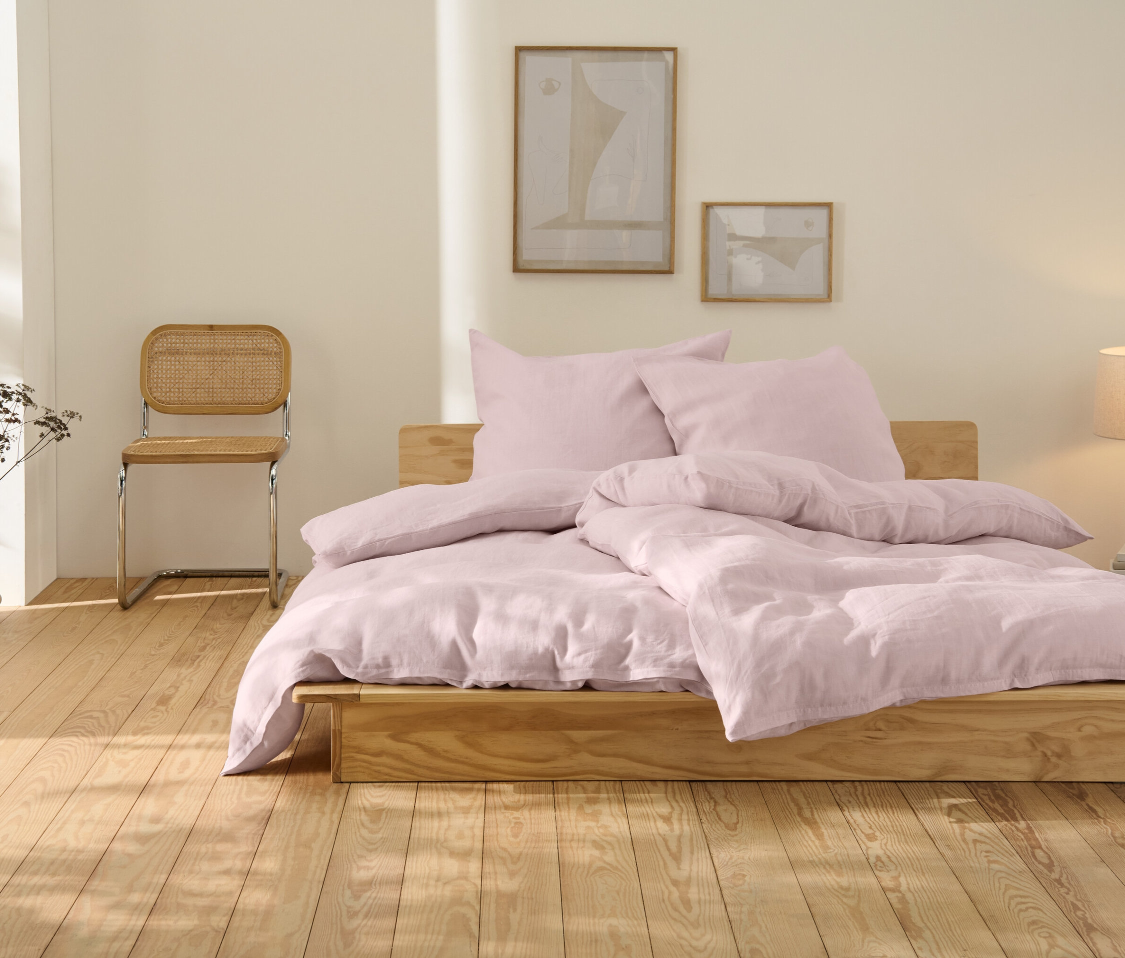 Ružové ľanové posteľné obliečky nadmernej veľkosti ležia na drevenej posteli.