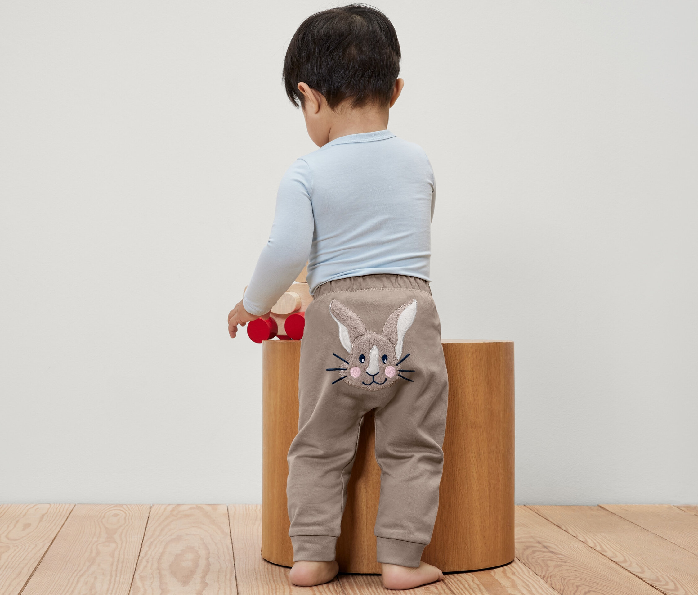 Chlapček stojí chrbtom, má na sebe detské nohavice s obrázkom králika.