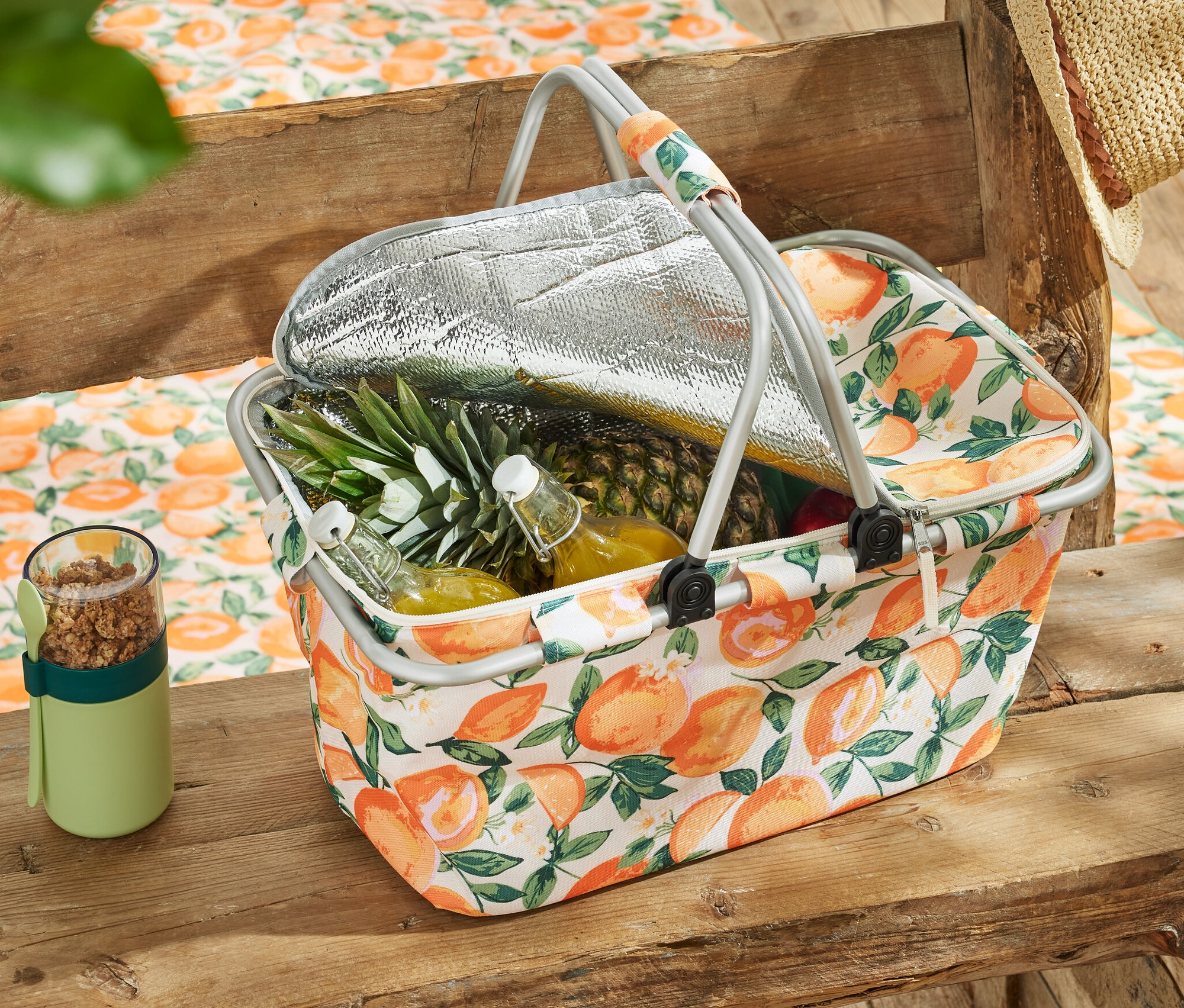 Chladiaci košík s ovocím a nápojmi na drevenom stole.