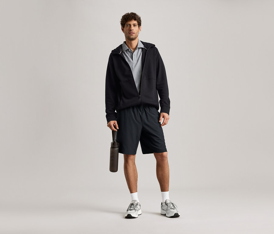 Muž v čiernej mikine s fľašou na pitie