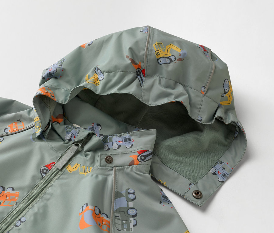 Detail olivovozelenej detskej bundy s kapucňou, potlačenej stavebnými vozidlami.