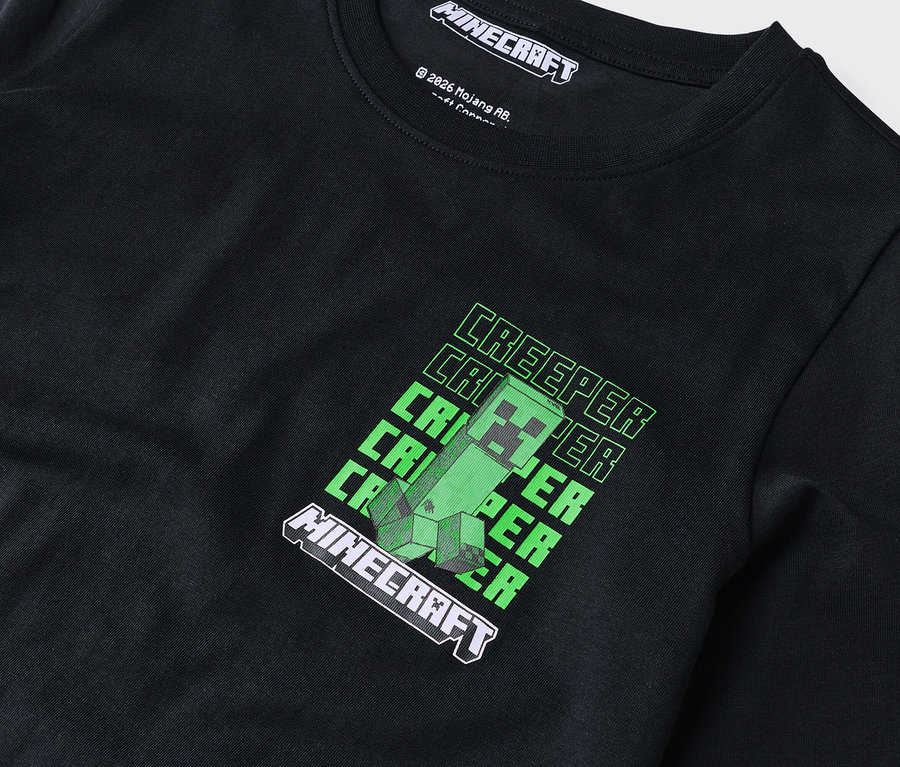 Detail čierneho trička s dlhým rukávom so zeleným motívom Minecraft Creeper.