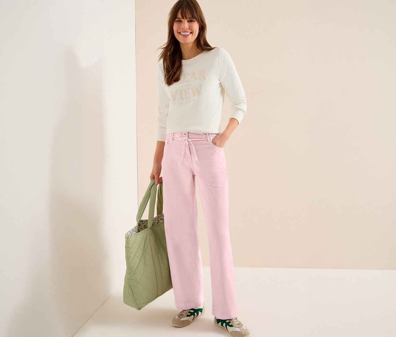 Žena s taškou má na sebe svetlý top a ružové džínsy CECIL »Neele«.