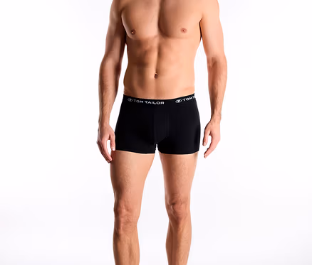 Usmievajúci sa muž má na sebe čierne boxerky TomTailor „Buffer“ s nápisom TomTailor na páse a pozerá sa dole.