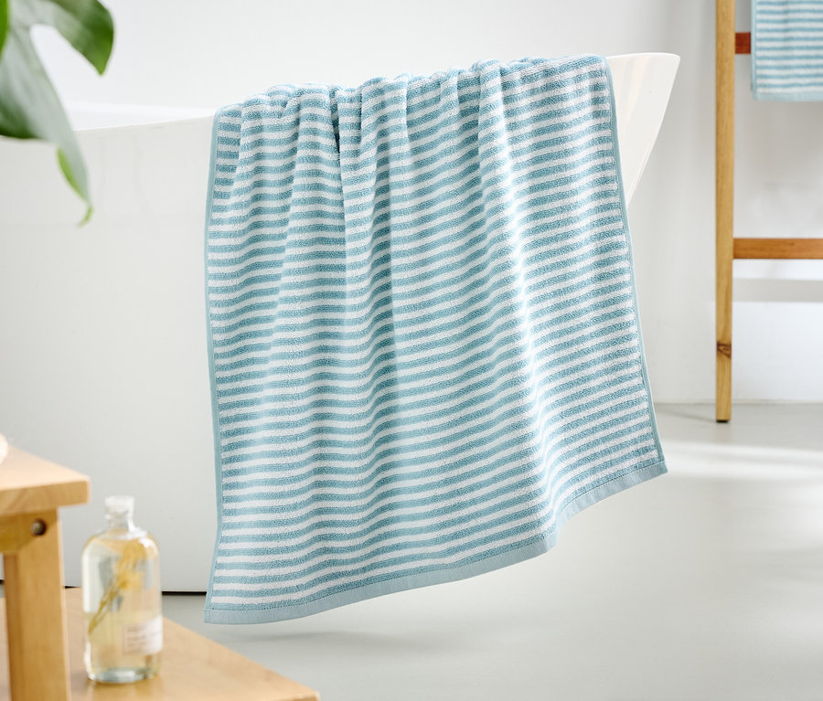 Modro-biely pruhovaný uterák visí z okraja vane.