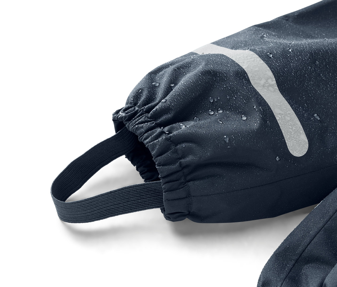 Detailný záber na tmavomodrý rukáv s elastickou manžetou a popruhom na nohy, pokrytý kvapkami vody.