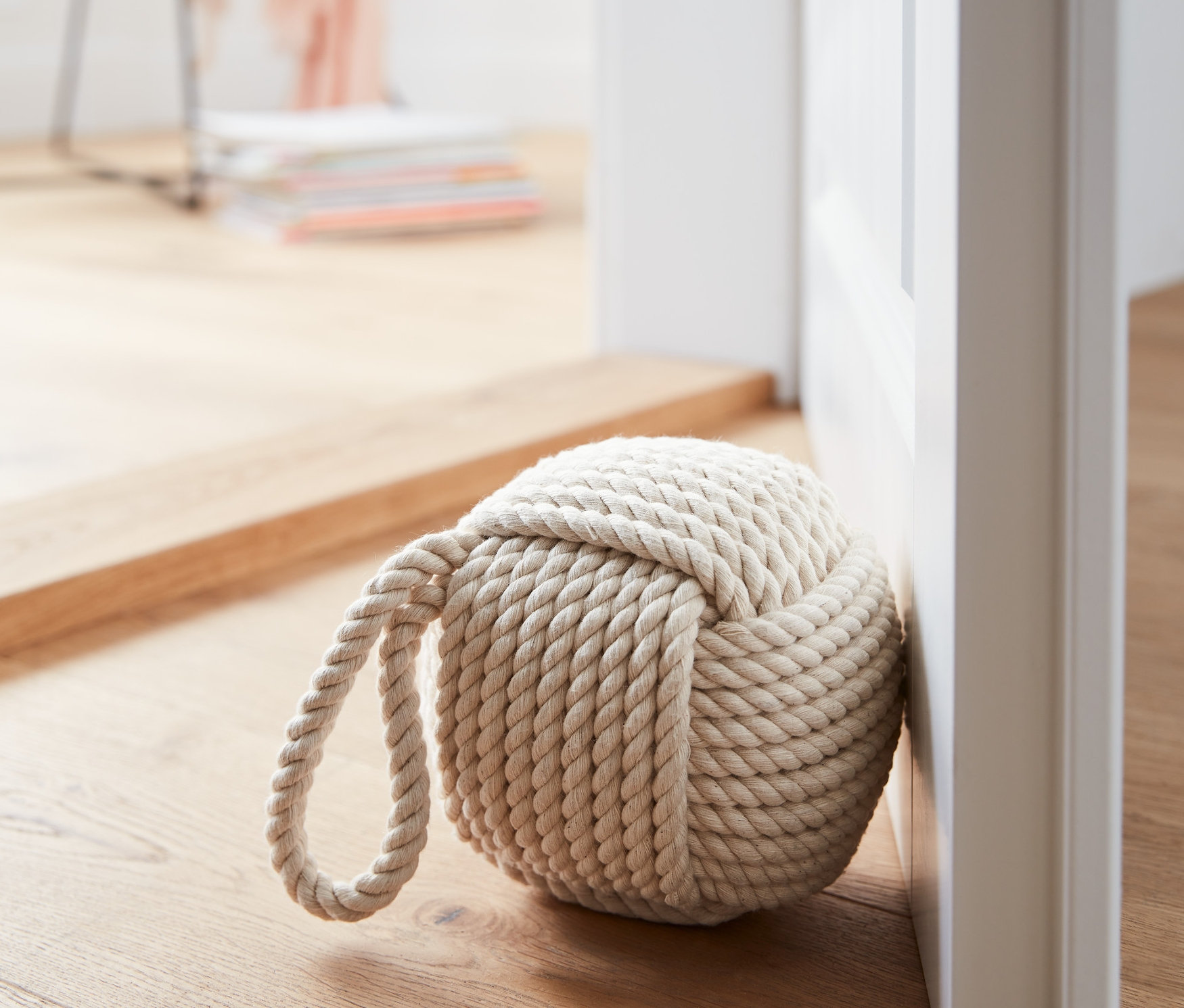 Lanová zarážka do dverí pri bielych dverách na drevenej podlahe.