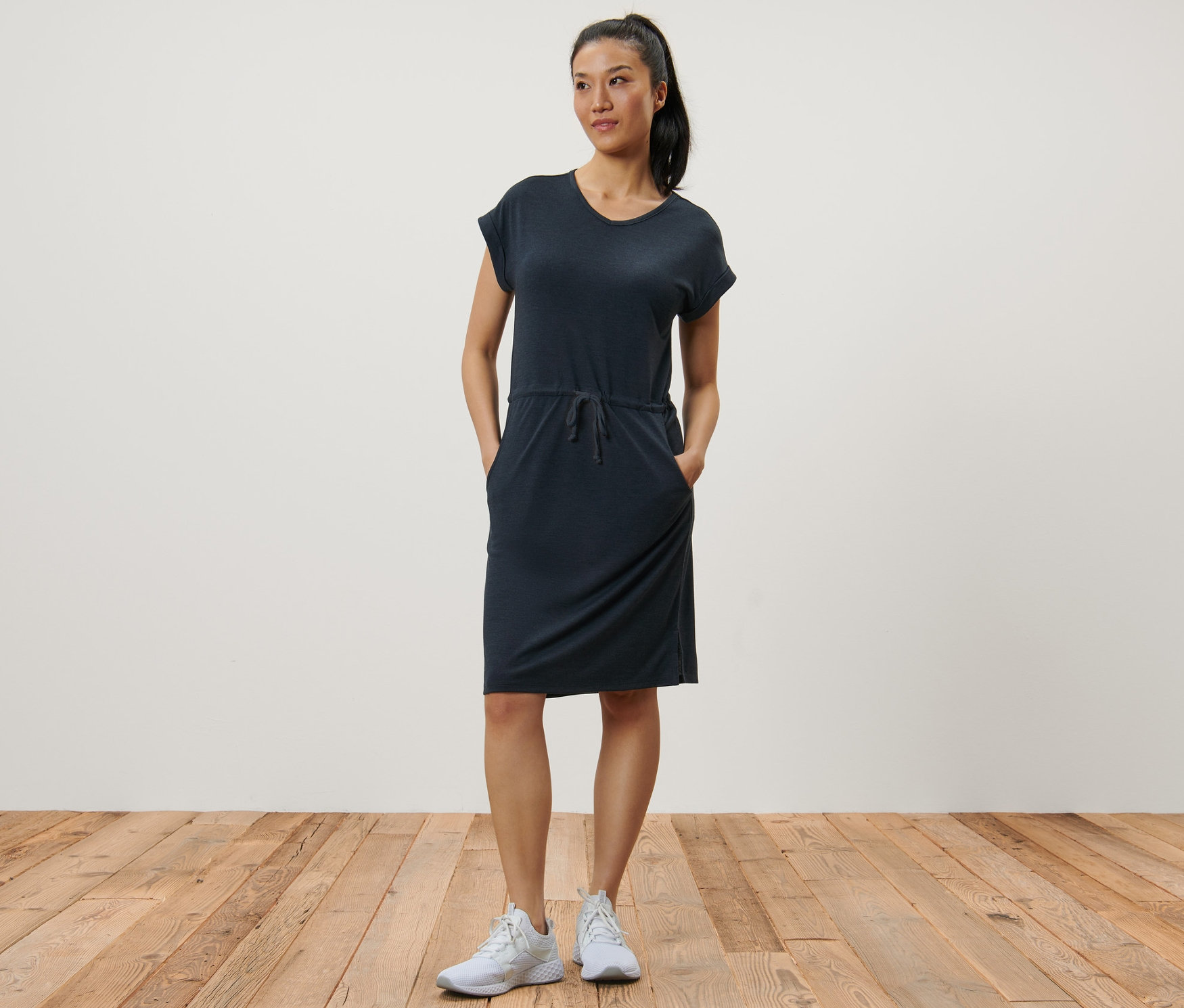 Žena pózuje v tmavomodrých outdoorových šatách.