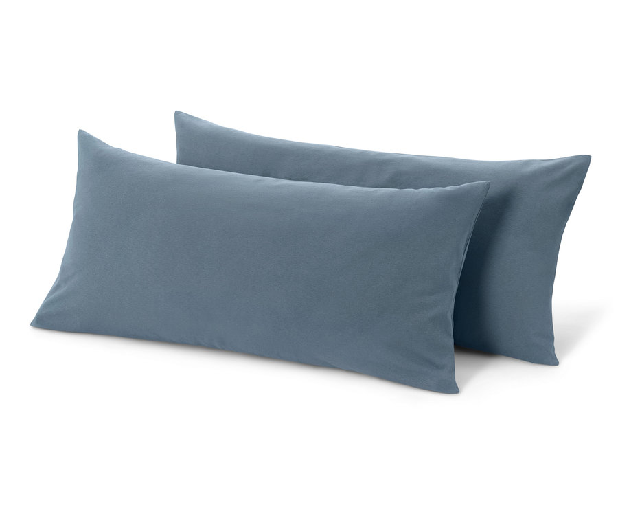 Dve modré džersejové obliečky na vankúše ležia na bielom pozadí.