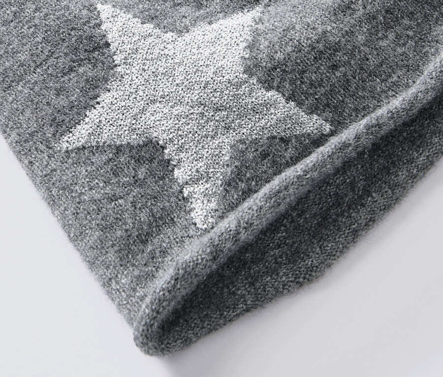 Detail šedej pletenej čiapky beanie s trblietavou hviezdou.