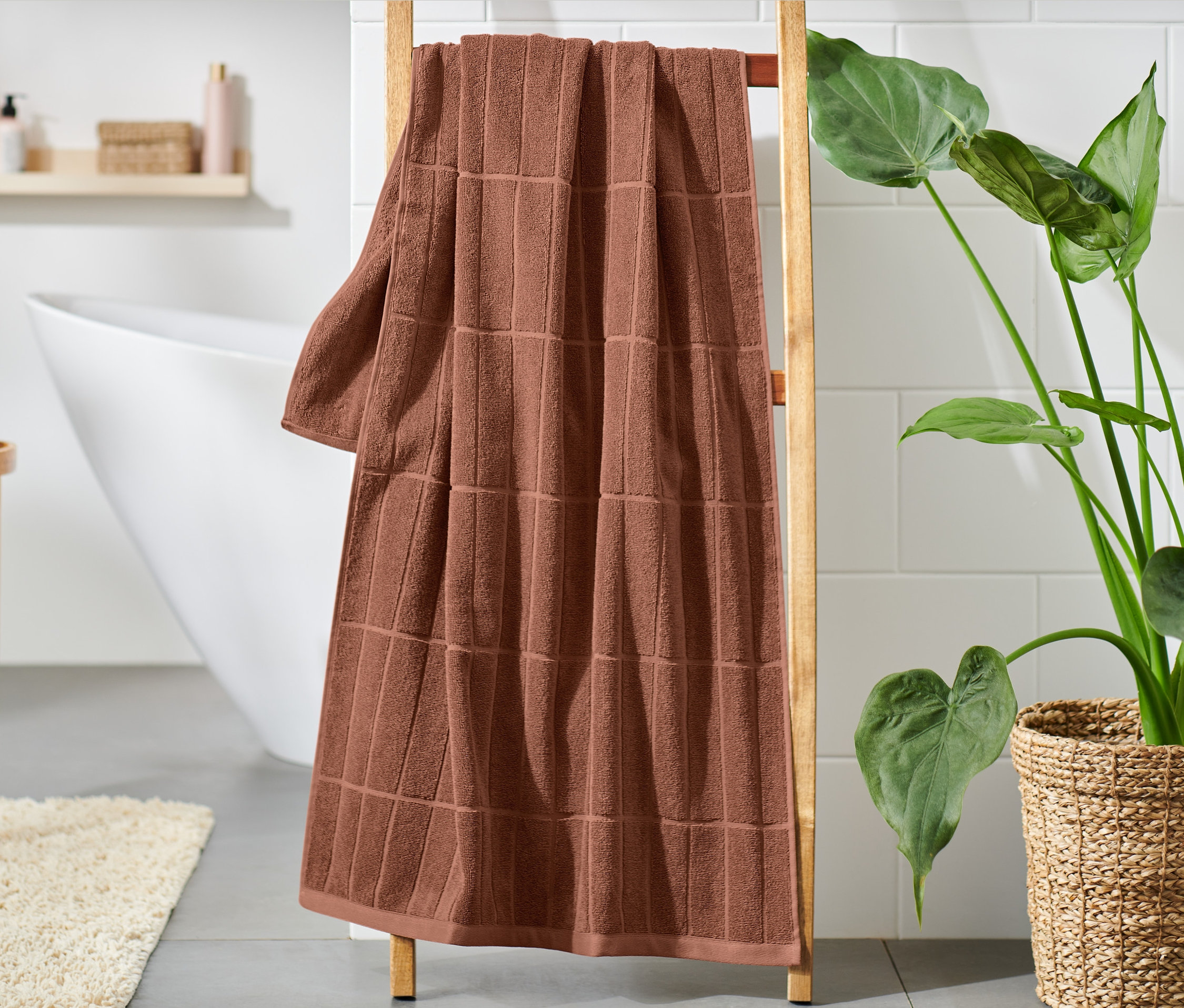 Hrdzavočervená osuška prémiovej kvality visí na drevenom rebríku v kúpeľni.