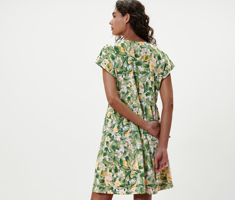 Žena pózuje chrbtom k fotoaparátu v džersejových šatách s potlačou.