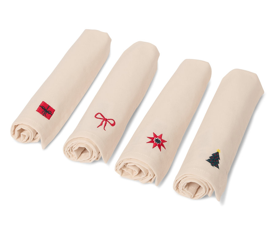 Štyri zrolované béžové obrúsky s vianočnými motívmi.
