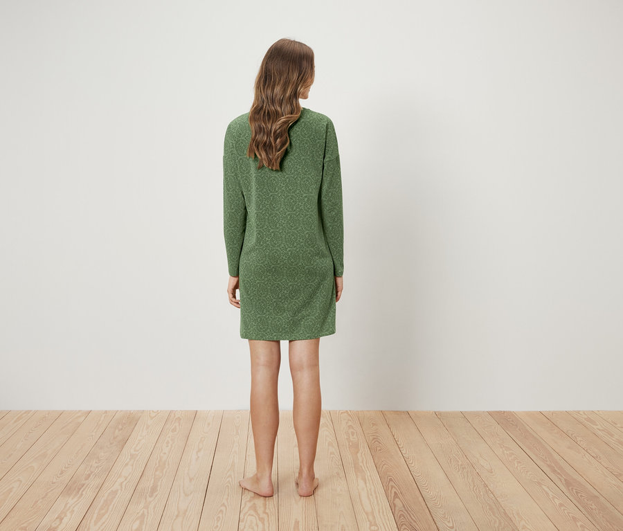 Žena stojí chrbtom k fotoaparátu a má na sebe zelené šaty.