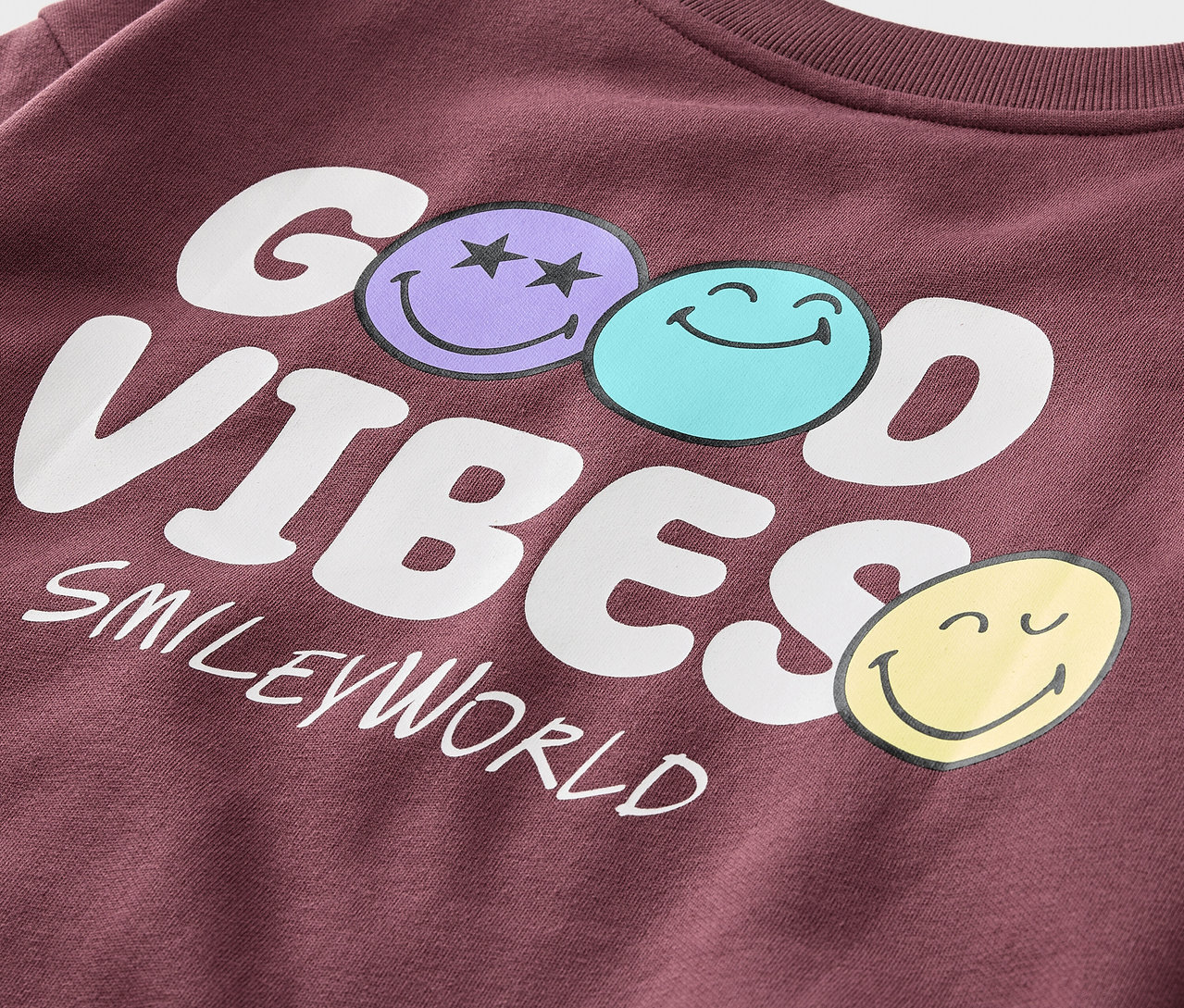 Detail bordovej mikiny Kinder-Sweatshirt SMILEYWORLD® s nápisom GOOD VIBES a tromi smajlíkmi.
