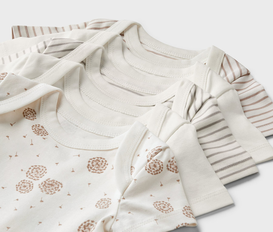 Detailný pohľad na päť dojčenských body s krátkym rukávom, vrátane jedného s potlačou púpavy a ďalších s pruhmi.