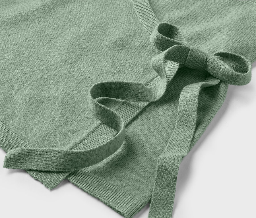 Detail svetlozeleného svetra so zaväzovaním.