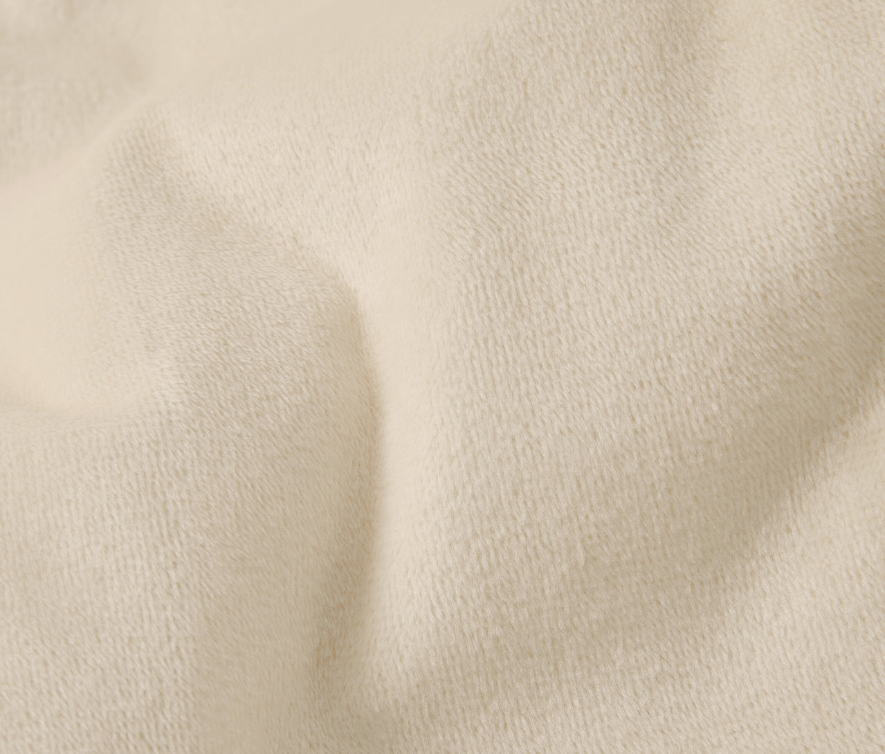 Detailný záber krémovej textílie s jemnou textúrou a záhybmi.