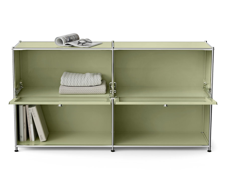 Zelená modulárna skriňa s knihami, dekou, okuliarmi a novinami.