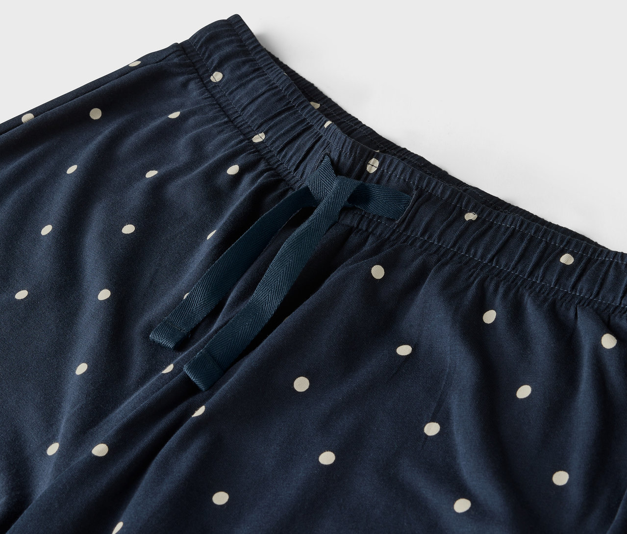 Detail modrých nohavíc s bielymi bodkami, elastickým pásom a sťahovacou šnúrkou.