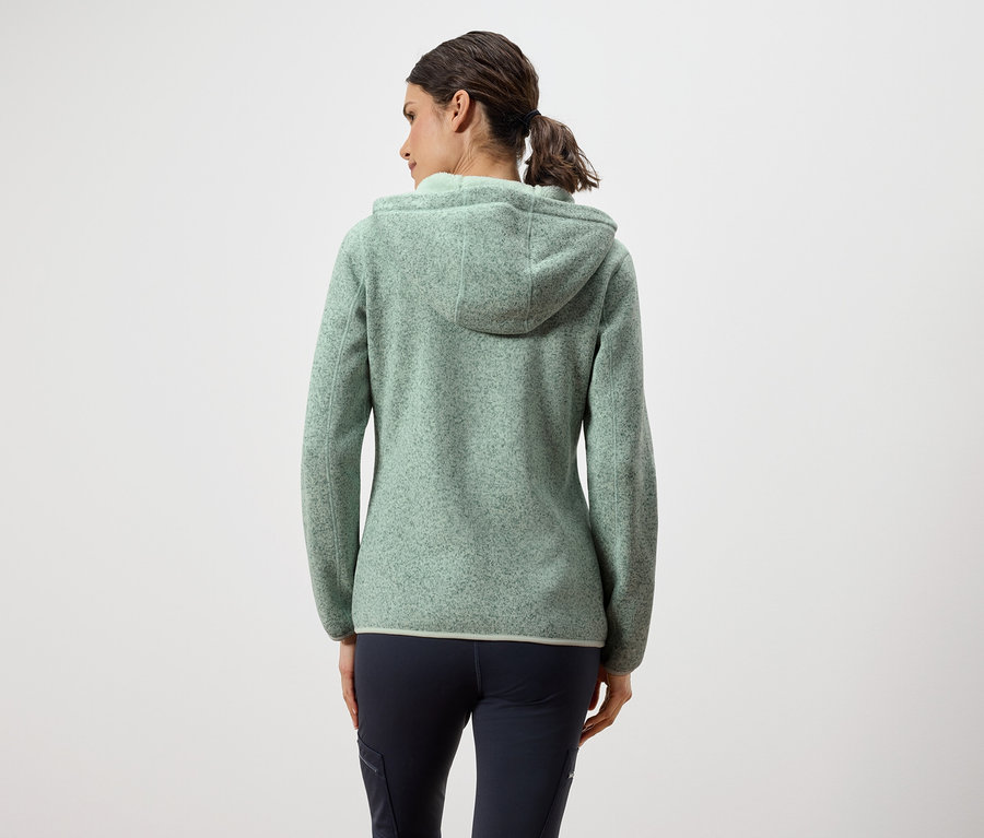 Zozadu je vidieť žena v zelenej mikine s kapucňou a tmavomodrých nohaviciach.