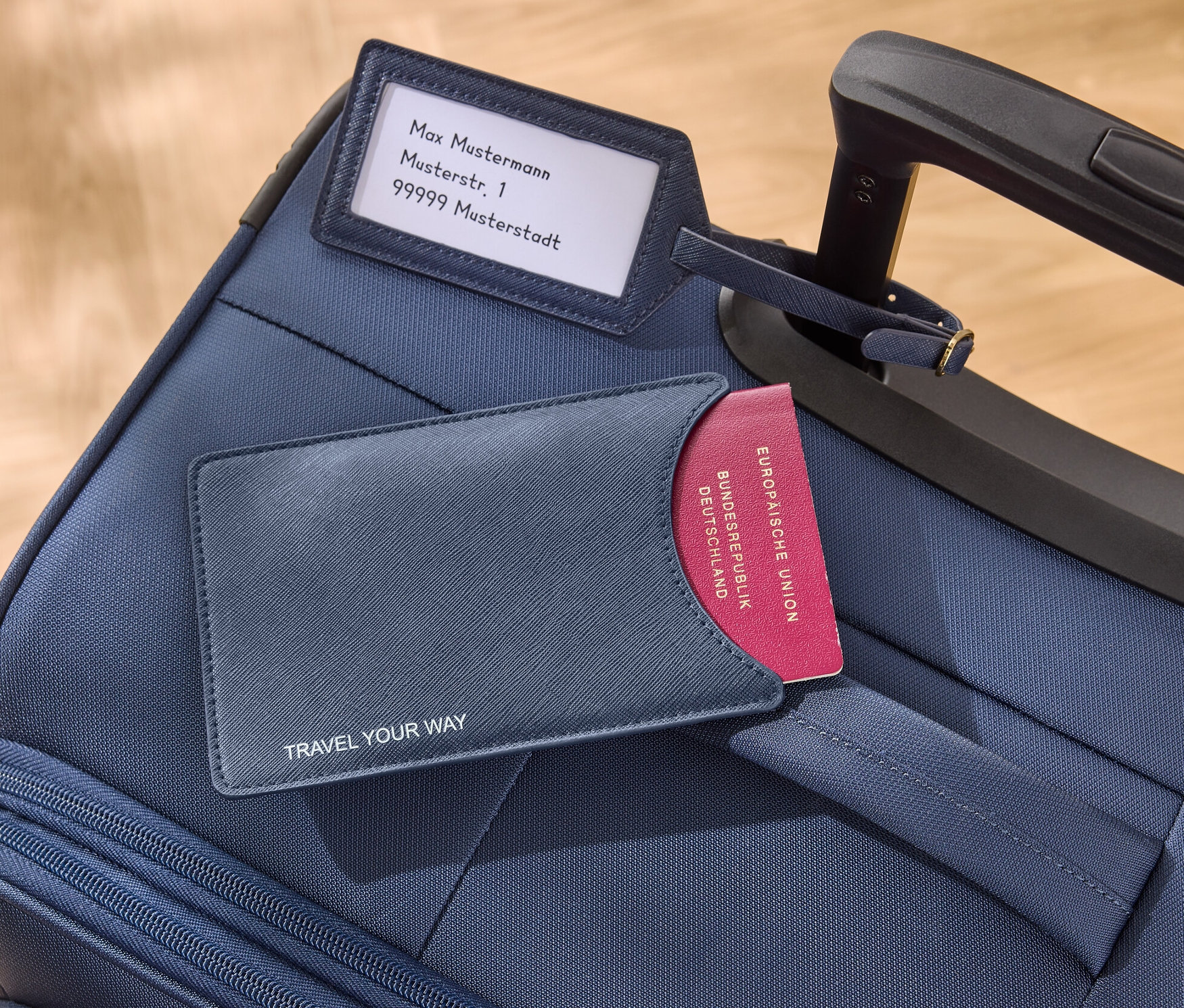 Na modrom kufri leží modré puzdro na pas a prívesok na kufor.