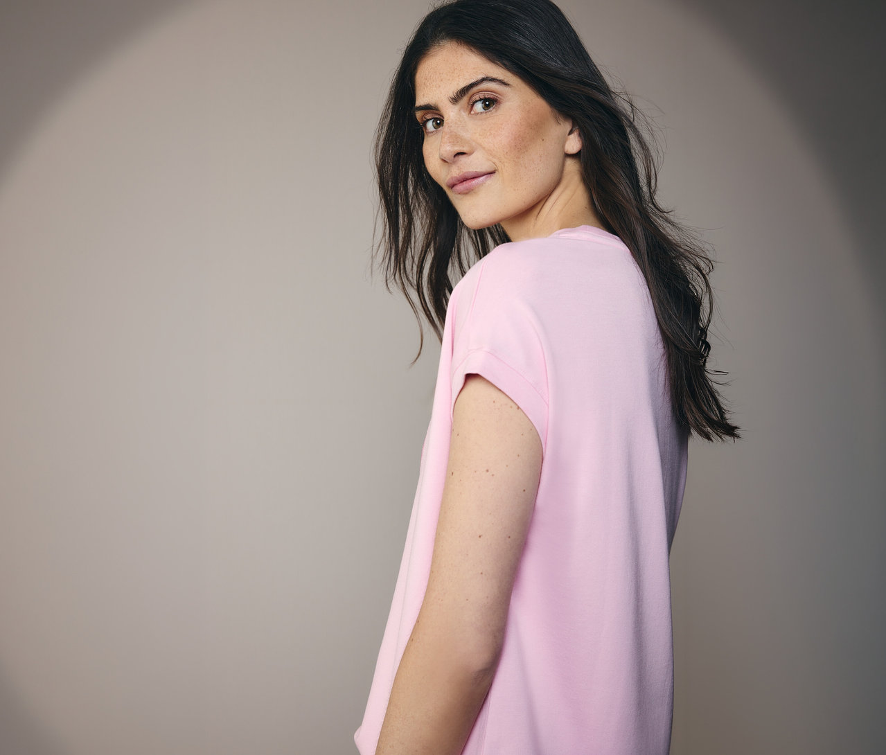 Žena v tričku CECIL sa pozerá cez rameno.