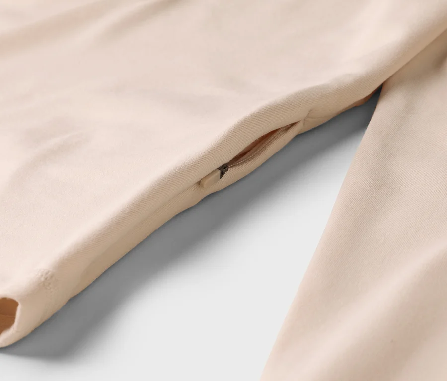 Detail béžového odevu s vreckom na zips na boku.