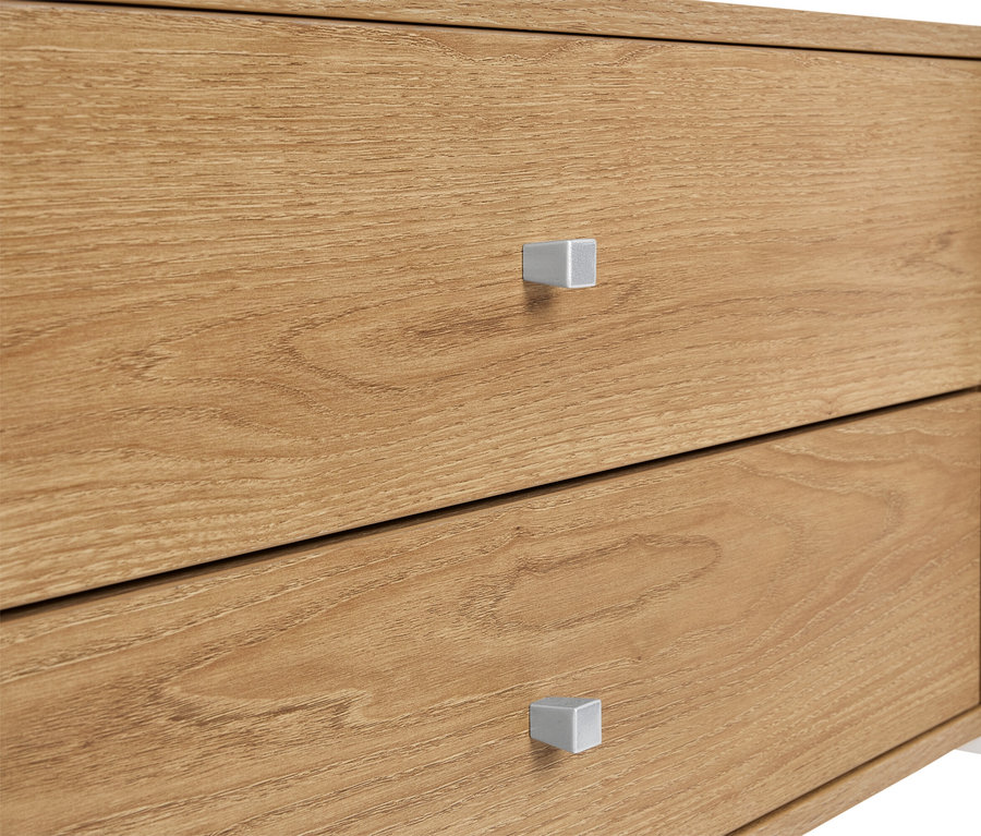 Detailný záber na drevenú skrinku s dvomi zásuvkami a striebornými úchytkami.