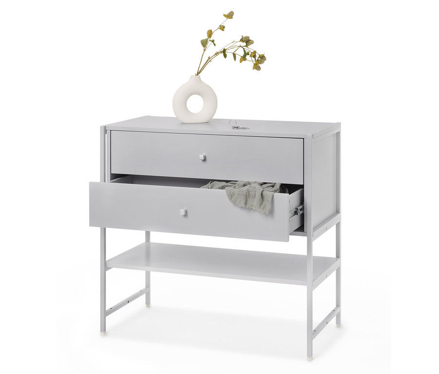 Sivá komoda s dvoma zásuvkami, z ktorých jedna je otvorená, a poličkou pod ňou, s látkou vo vnútri a vázou s rastlinou na vrchu.