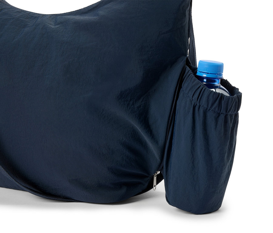 Detailný záber na tmavomodrú tašku s fľašou vody v bočnom vrecku.