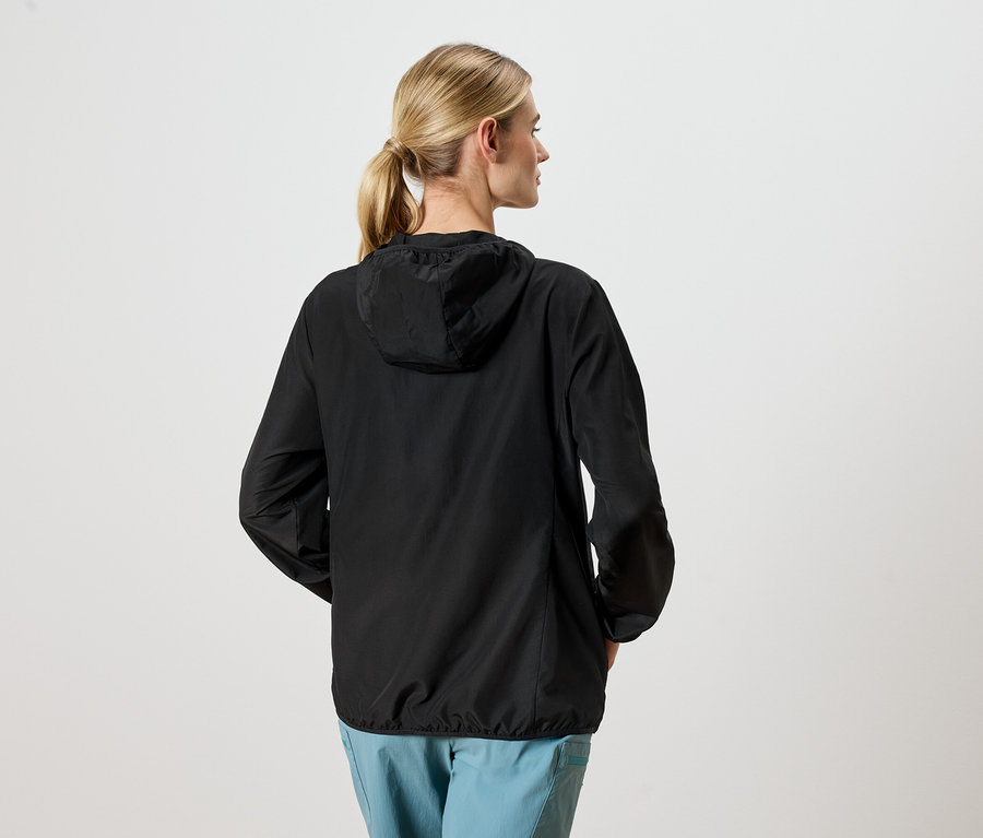 Žena zozadu v čiernej bunde a modrých nohaviciach.