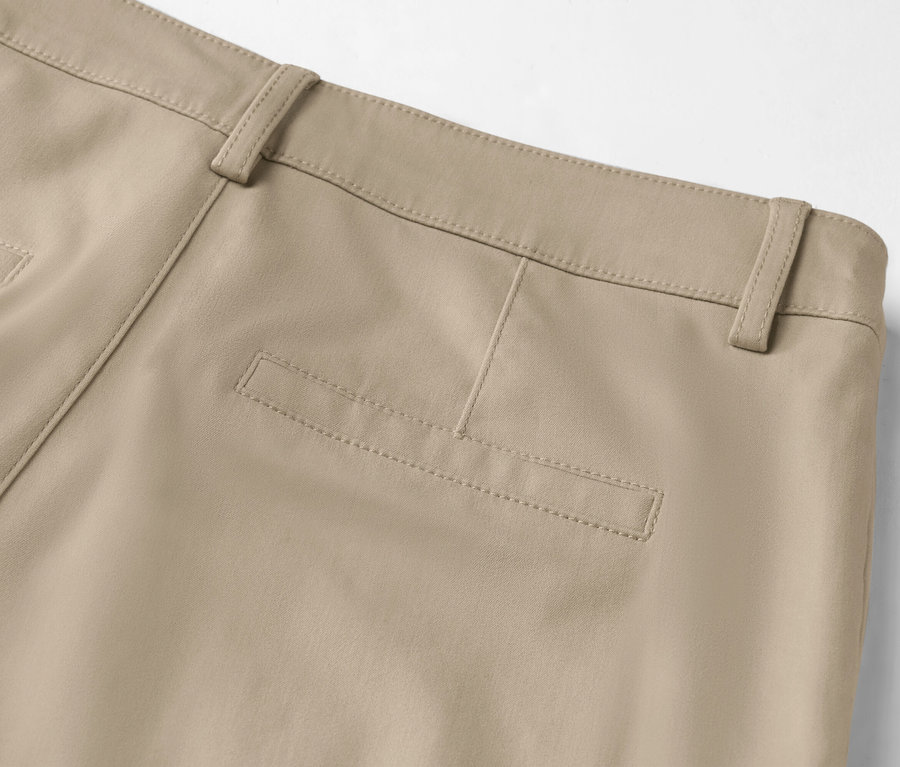 Detail záberu zadnej časti béžových nohavíc s vreckom na zadku a pútkami na opasok.