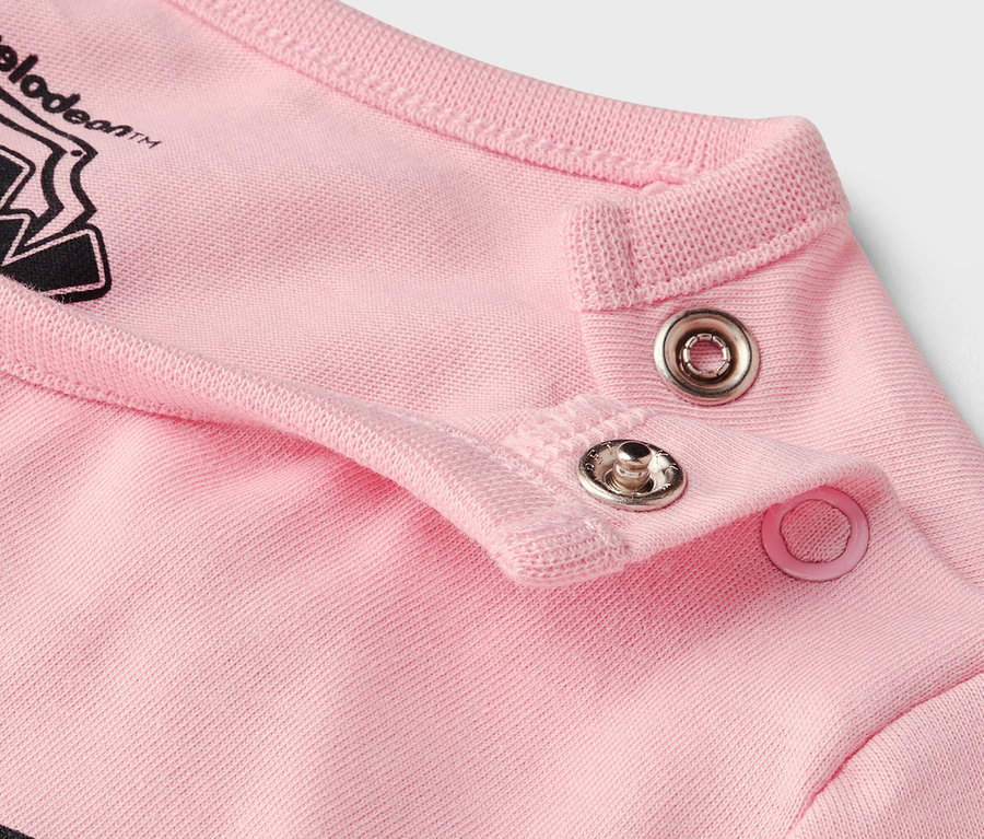 Detail záberu patentiek na ružovom odeve.