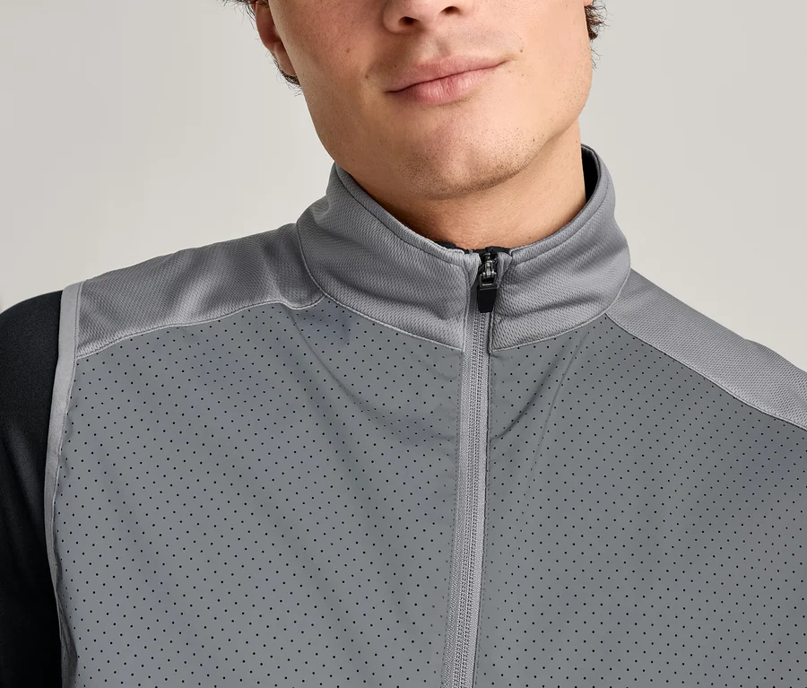 Detail muža v šedej veste na zips cez čierne tričko s dlhým rukávom.