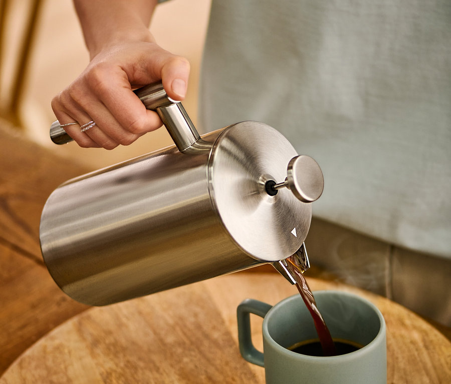 Žena nalieva kávu z dvojstennej kanvice french press z ušľachtilej ocele s objemom 900 ml do hrnčeka.